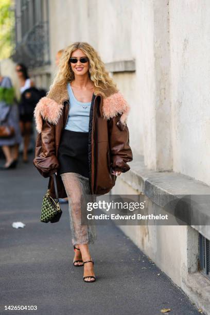 Emili Sindlev wears a green and black triangular print pattern with black shiny leather Triangle handbag from Prada, black sunglasses, gold earrings,...