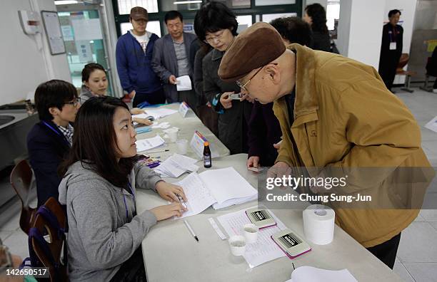 South Koreans queue up to cast their votes for new members of the National Assembly in a polling station at the Yuido Elementary School on April 11,...