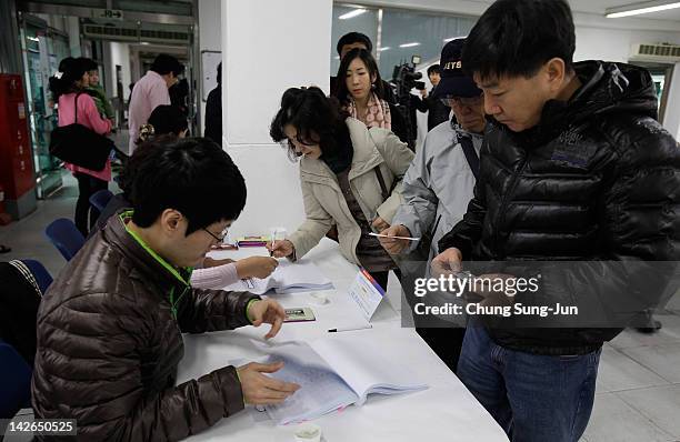 South Koreans queue up to cast their votes for new members of the National Assembly in a polling station at the Yuido Elementary School on April 11,...