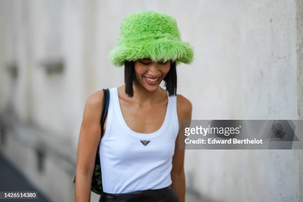 Molly Chiang wears a green fluffy bob hat, a white tank-top from Prada, outside Prada, during the Milan Fashion Week - Womenswear Spring/Summer 2023...