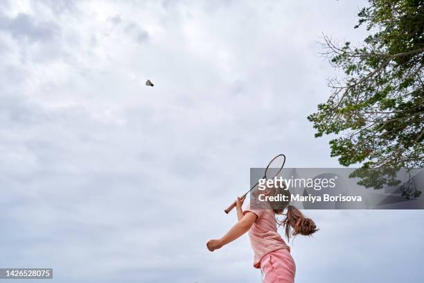 a girl in pink is playing badminton. bottom view. - playing badminton stock-fotos und bilder