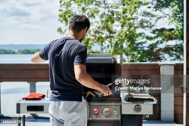 a korean man cooks wings on a gas grill. - backyard grilling stockfoto's en -beelden