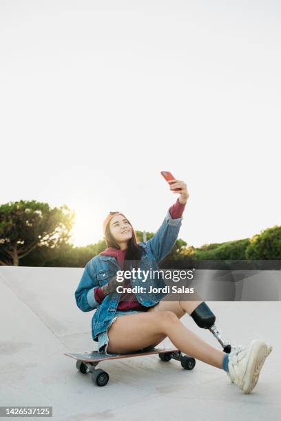 amputee woman with a skateboard in a skatepark - feet selfie woman stockfoto's en -beelden