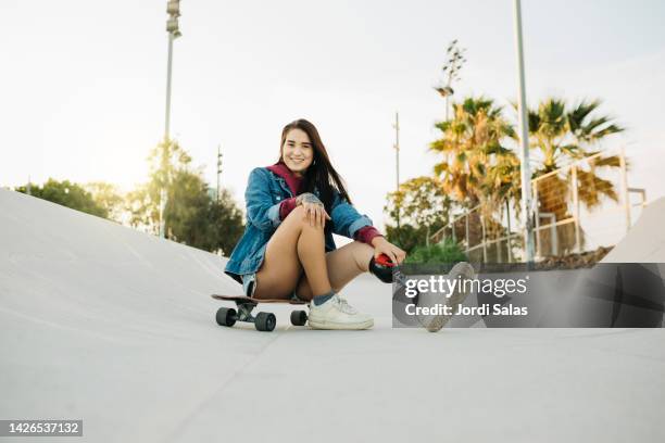 amputee woman with a skateboard in a skatepark - latina legs stockfoto's en -beelden