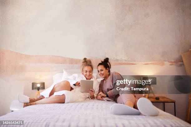 lgbtq female couple relaxes in a hotel bedroom. - lesbian bed stock pictures, royalty-free photos & images