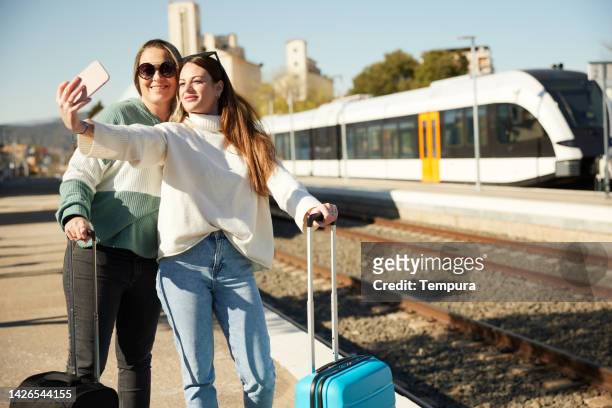 women traveling by train make a selfie on the station platform. - railroad station platform stockfoto's en -beelden