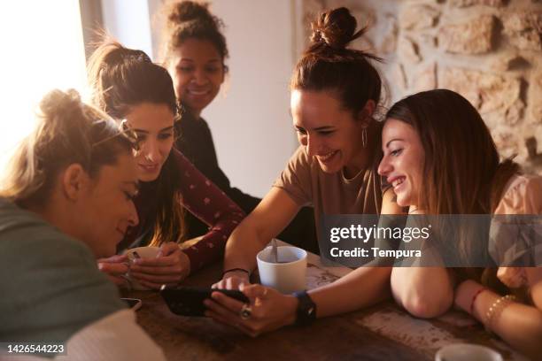 grupo de amigos en un apartamento de alquiler mirando un teléfono inteligente. - cotilleo fotografías e imágenes de stock
