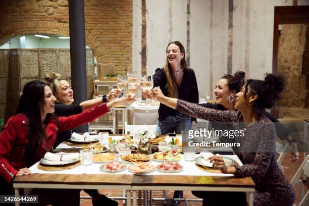 a group of friends toasts in a hotel dining hall. - luxury home dining table people lifestyle photography people stock pictures, royalty-free photos & images