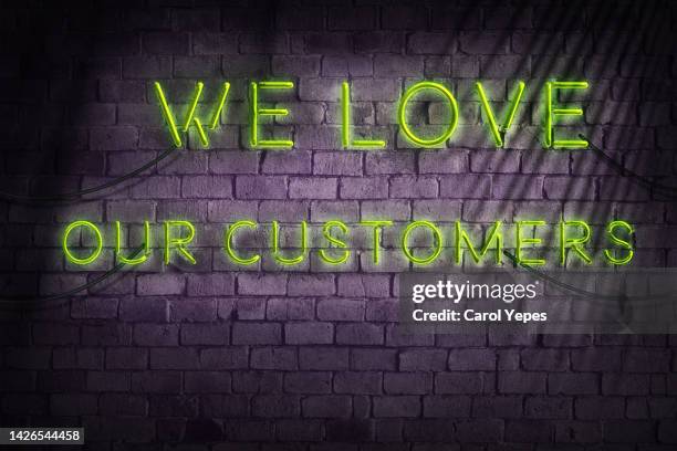 we love our customer message in neon light against brick wall - customer loyalty stock-fotos und bilder