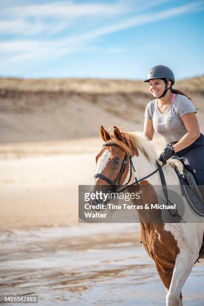 a young woman rides a painted horse on a lonely beach. - cabestro fotografías e imágenes de stock