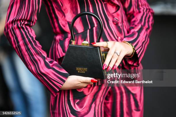 Guest wears a black and neon pink print pattern blazer jacket, black and neon pink print pattern suit pants, a black shiny leather handbag from...