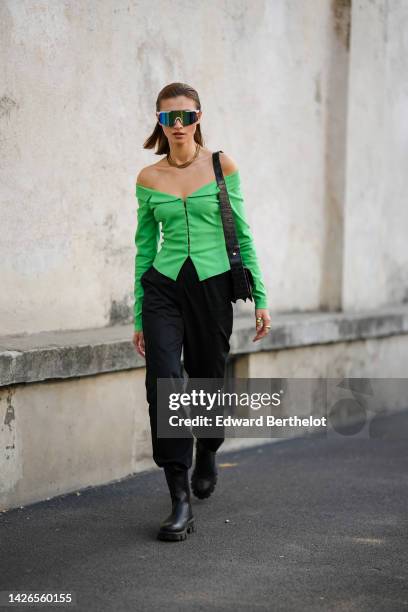 Guest wears navy blue to green reflect futurist sunglasses, a green shoulder-off / long sleeves / buttoned jacket, a black shiny leather crocodile...