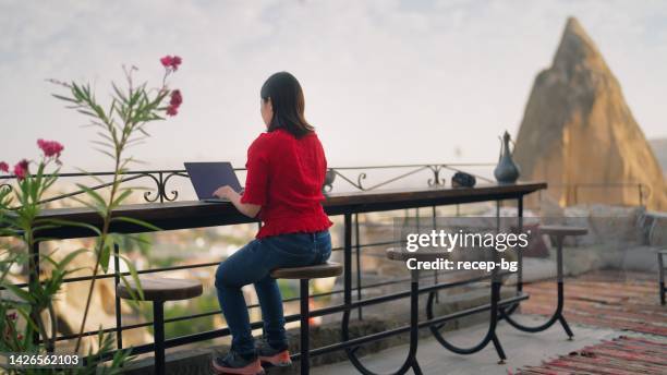 young female freelancer tourist using her laptop at rooftop patio of hotel - japanese people typing stock pictures, royalty-free photos & images