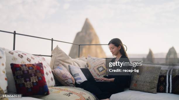 young female freelancer tourist using her laptop at rooftop patio of hotel - wonderlust computer stock pictures, royalty-free photos & images