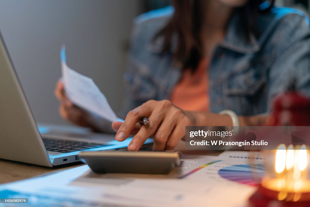 Close up of woman planning home budget and using calculator.