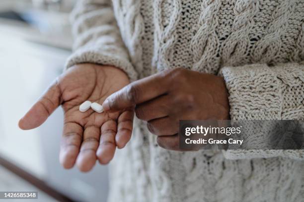 woman holds pills in palm of her hand - acetylsalicylizuur stockfoto's en -beelden