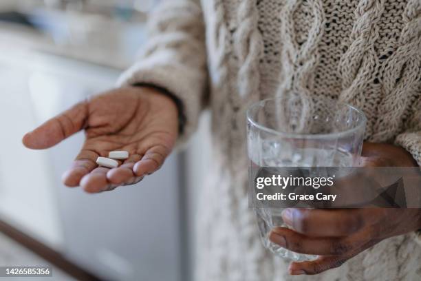 woman holds pills and glass of water - paracetamol stock-fotos und bilder