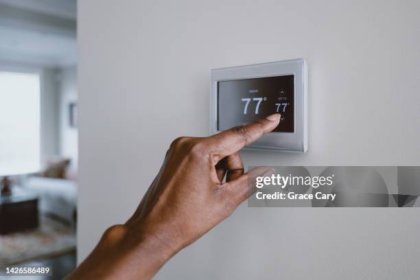 woman adjusts thermostat - air conditioner home stock pictures, royalty-free photos & images