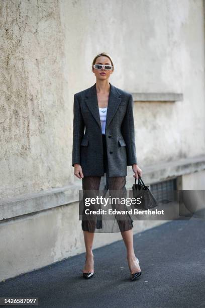 Guest wears white sunglasses, a white tank-top from Prada, a black bi material silk and fabric midi skirt from Prada, a black shiny leather handbag,...