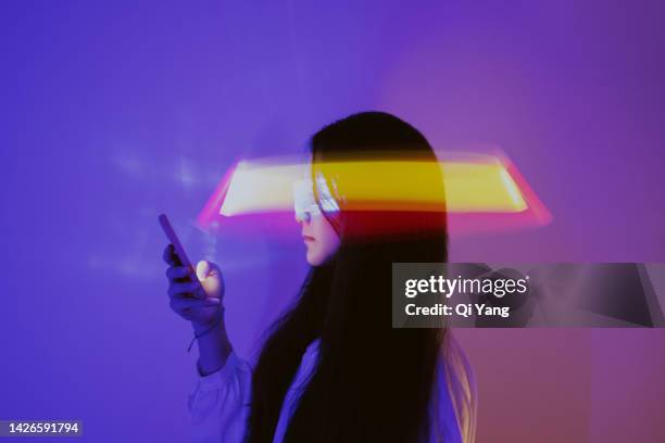 asian woman using smartphone surrounded by beams of light - smartphone hologram stockfoto's en -beelden