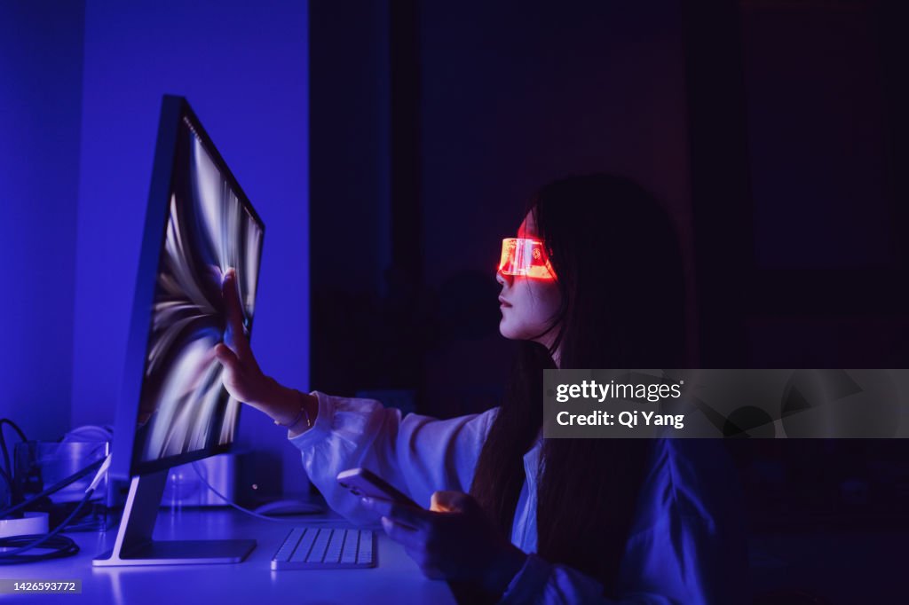 Asian woman touching computer screen at home office late at night