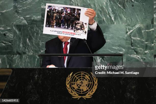 President of the State of Palestine Mahmoud Abbas holds up a photo as he speaks at the 77th session of the United Nations General Assembly at U.N....