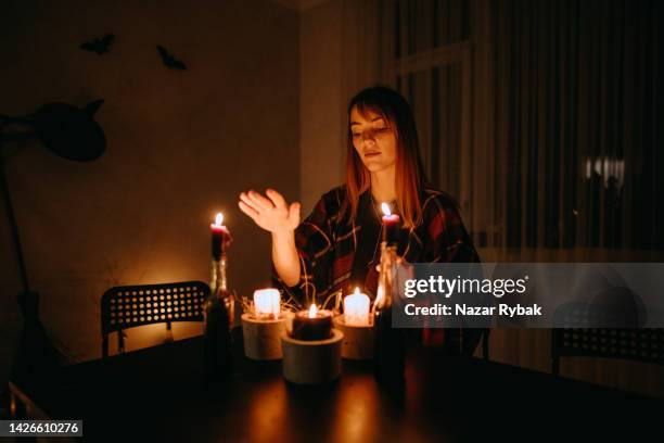 a woman conjuring on candles during halloween in a dark stylized room - trollformel bildbanksfoton och bilder