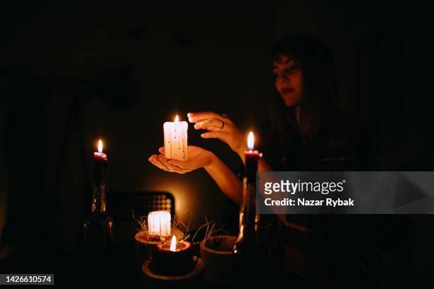 weibliche hand, die an halloween im dunkeln eine kerze hält - wizard stock-fotos und bilder
