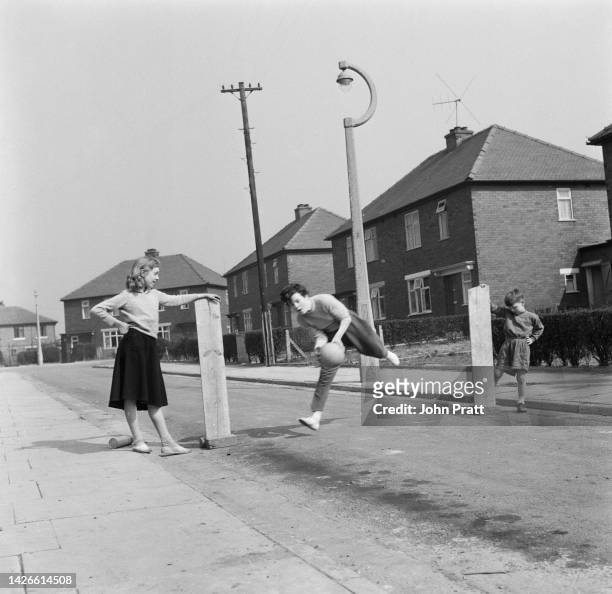 Year-old footballer, Margaret Wilde, at goalkeeping practice with goalposts held up by Brenda Brook and Trevor Howard in a street near their homes in...