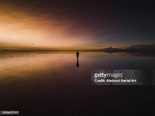 low angle drone shot showing a person on a flooded salt pan at sunset, salar de uyuni, bolivia - one man only stock pictures, royalty-free photos & images