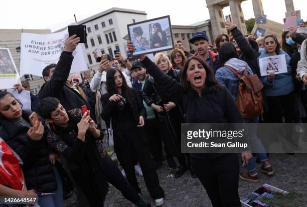 Female protester holds up photographs of Mahsa Amini before cuttinh her hair with scissors as an act of solidarity with women in Iran during a...