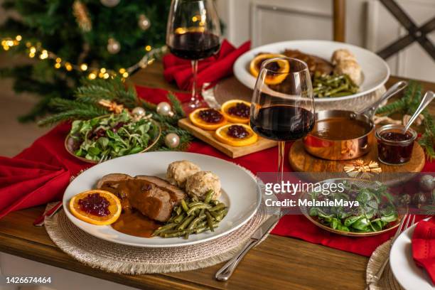 weihnachtsessen roastbeef wild mit soße und preiselbeeren in rustikaler küche zu hause - weihnachtsessen stock-fotos und bilder