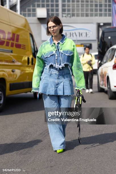 Guest is seen wearing denim cropped jacket with green paint and a denim skirt over denim pants at Etro show during the Milan Fashion Week -...