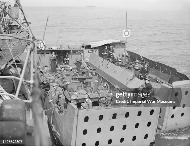 Landing craft containing a Bren carrier and soldiers alongside a destroyer having returned from the beaches during the Combined Operations daylight...
