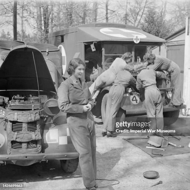 Princess Elizabeth beside the car on which she had undergone instruction in vehicle maintenance, and fellow trainees at the Auxiliary Territorial...