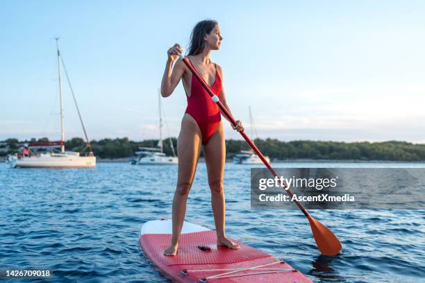 young woman paddles sup on sea - paddleboard stockfoto's en -beelden