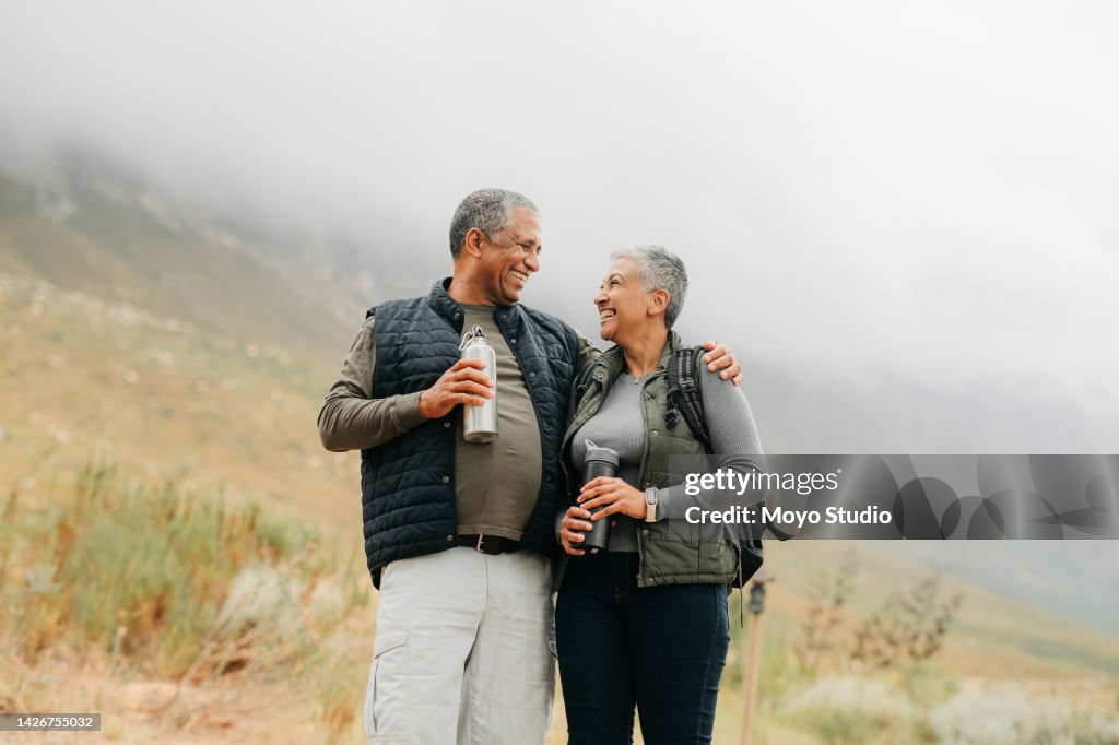 Senior couple hiking in the mountains in nature, walking for fitness on holiday in mountain and exercise during vacation in the countryside together. Happy latino man and woman on walk for health