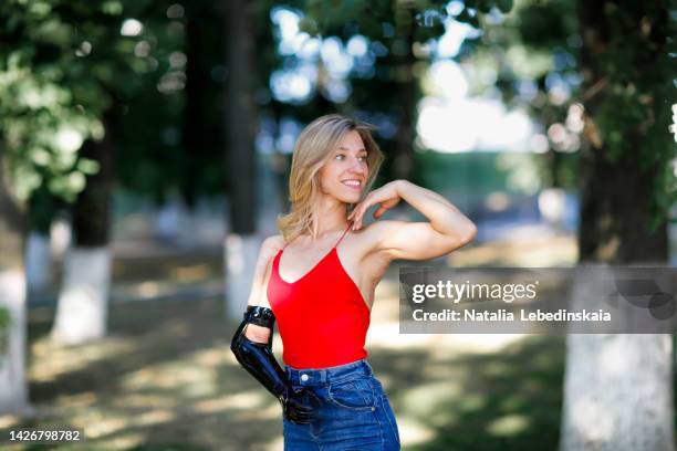 slim fit woman woman with a prosthetic arm in the park in the summer. - artificial arm stock pictures, royalty-free photos & images