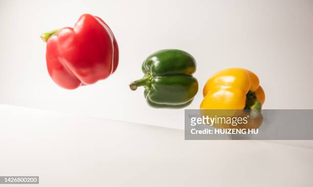 green, yellow and red bell pepper flying on a white background - yellow bell pepper stock-fotos und bilder