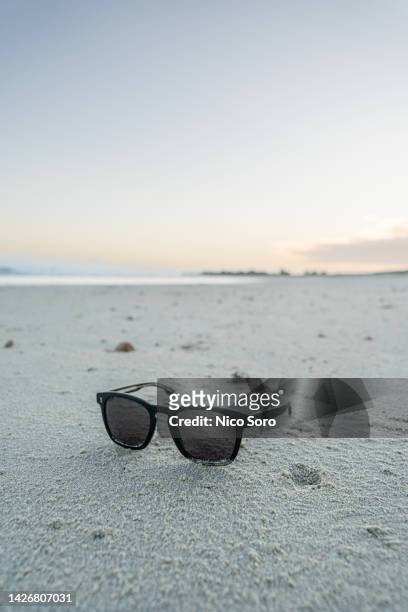 a pair of sunglasses on a beautiful beach at sunset - beach flat lay stock pictures, royalty-free photos & images
