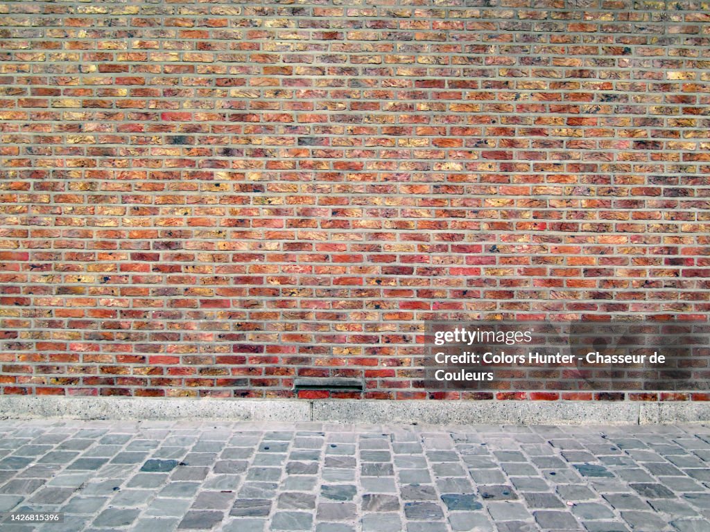 Empty brown brick wall and gray cobblestone sidewalk in Brussels, Belgium