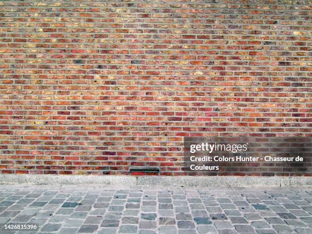 empty brown brick wall and gray cobblestone sidewalk in brussels, belgium - adoquinado fotografías e imágenes de stock