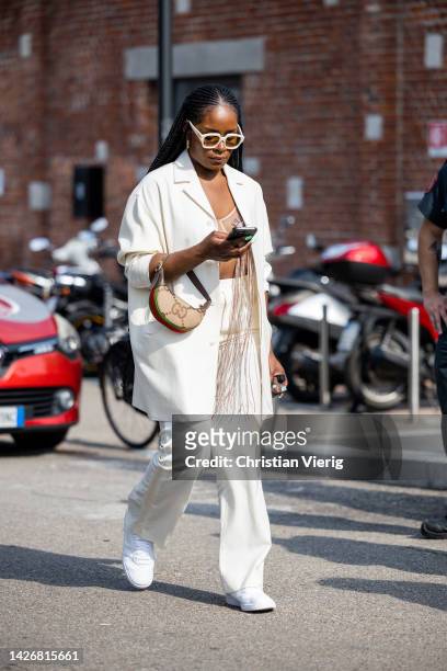 Guest wears white blazer, pants, beige bag outside Gucci during the Milan Fashion Week - Womenswear Spring/Summer 2023 on September 23, 2022 in...