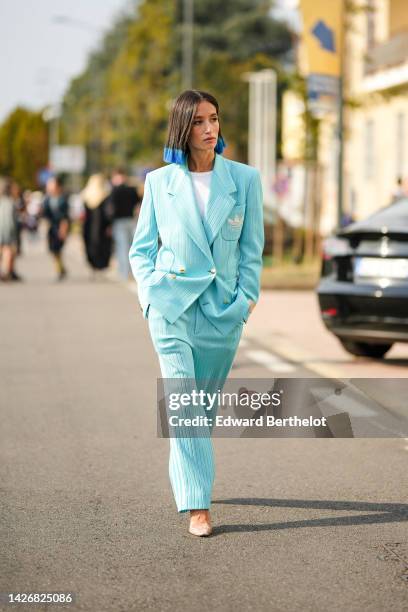 Alexandra Guerain wears a white t-shirt, a pale blue wool blazer jacket from Gucci x Adidas, matching mint blue wool suit pants from Gucci x Adidas,...