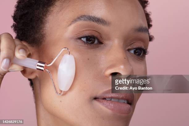close-up of woman using facial roller - 玉石滾輪 個照片及圖片檔