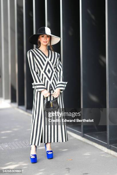 Heart Evangelista wears a half black and half white felt hat from Gucci, silver and pink earrings, a pale gray and black striped print pattern jacket...