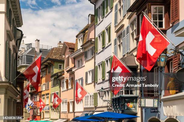 swiss flags on houses along street - schweizer flagge stock-fotos und bilder