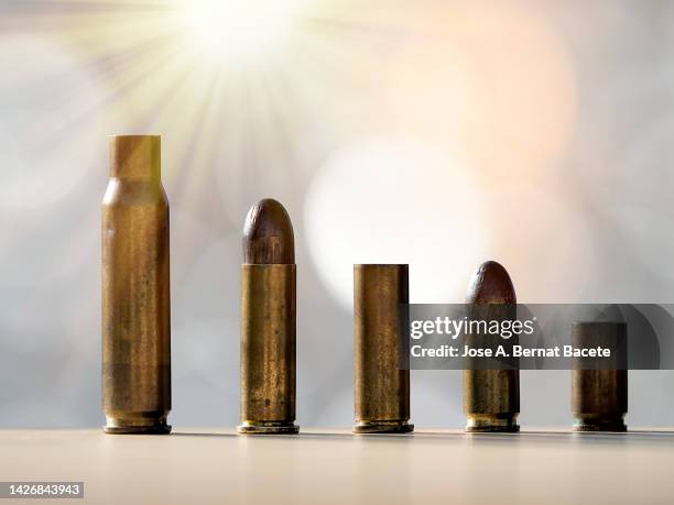 bullets and shell casings from a war weapon illuminated by sunbeams. - cartridge stock pictures, royalty-free photos & images