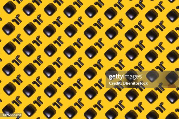 pattern of wireless black headphones next to charger, on yellow background. concept of audio, music, radio, podcast, listening, wireless and bluetooth technology. - electronic music 個照片及圖片檔