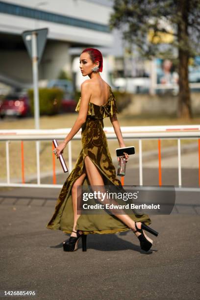 Guest wears a silver large earring, a khaki tulle and velvet print pattern asymmetric shoulder / square neck / long slit dress, black shiny leather...